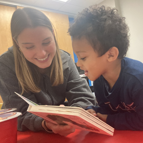 A boy is reading from a children's book with one of our speech-language experts